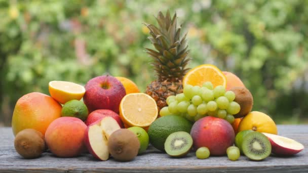木製のテーブルの上に様々な熟した果物のセットを閉じます おいしい健康的な果物 健康食品の概念 — ストック動画