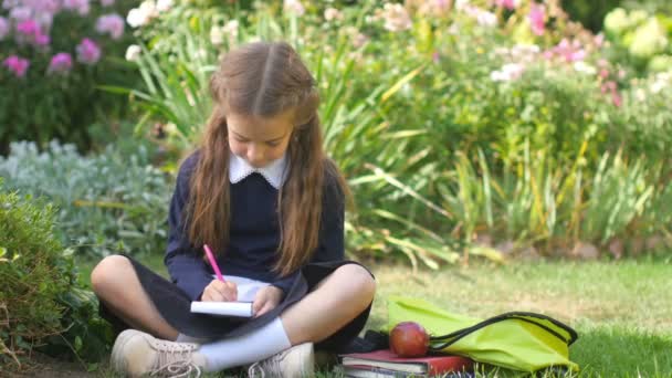 School Meisje Schoolmeisje Zit Het Gras Schrijft Het Notitieboekje Uhd — Stockvideo