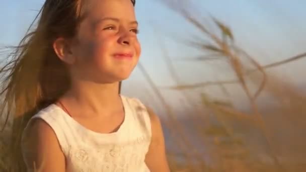 日没時に屋外でかわいい女の子の肖像画 太陽と小石を見ると — ストック動画