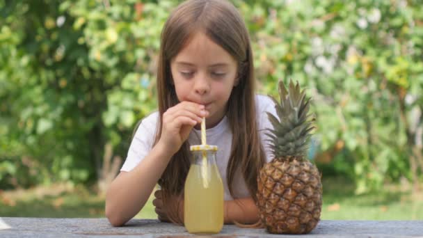 Kız Bahçedeki Ahşap Masada Meyve Suyu Içiyor Şişede Portakal Ananas — Stok video