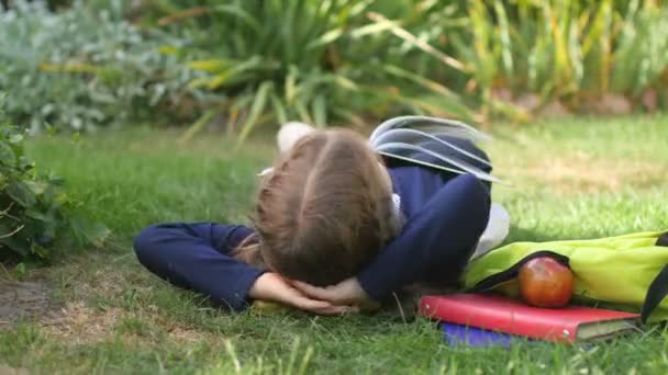 一个女学生拿着一本书躺在草地上 一个人在公园里休息 孩子们在做梦儿童教育概念 — 图库视频影像