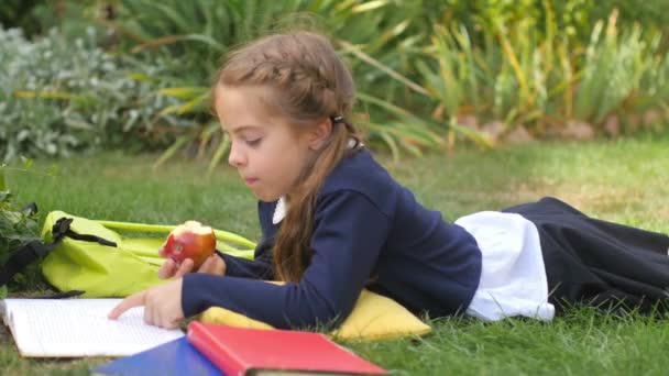 Een Schoolmeisje Ligt Het Gras Met Een Appel Die Een — Stockvideo