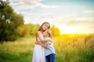 Tatlı çocuklar akşam parkında yürüyorlar. Yürüyüş için el ele tutuşun ve sohbet edin. Çocuklar rahatlar ve dışarıda oynarlar. Çocukluk.