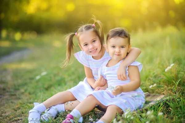 日落时 可爱的孩子们正在公园里散步 女孩们坐在草地上 轻轻拥抱 孩子们在户外玩耍和玩乐 — 图库照片