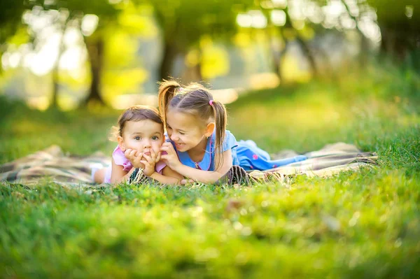 かわいい子供たちは日没時に公園で遊ぶ 女の子は芝生の上で遊んで楽しんで横になっています 子供たちが遊んで楽しい屋外 — ストック写真