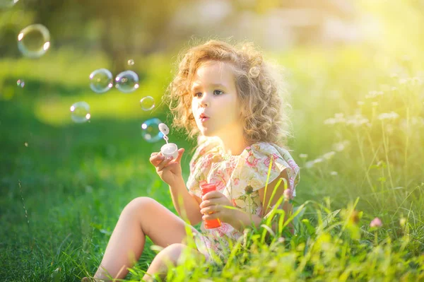 Menina Bonito Sopra Bolhas Sabão Enquanto Sentado Grama Parque Pôr — Fotografia de Stock