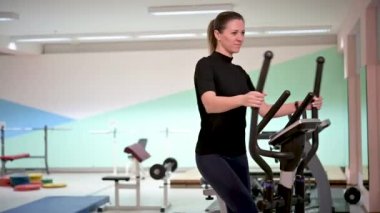 Güzel kız Orbitrek beden eğitimi konseptini yönetiyor. Fitness ve sağlıklı yaşam tarzı konsepti. Sporcu kadın fitness merkezinde çalıştırma makinesi kullanıyor.