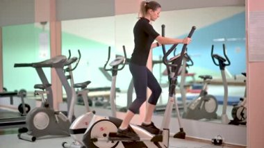 Güzel kız Orbitrek beden eğitimi konseptini yönetiyor. Fitness ve sağlıklı yaşam tarzı konsepti. Sporcu kadın fitness merkezinde çalıştırma makinesi kullanıyor.