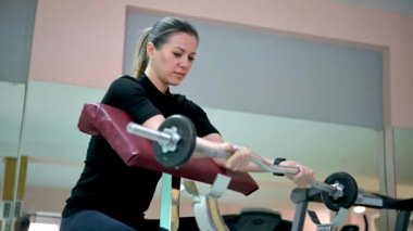 Spor salonunda ağırlık çalışmasıyla kol egzersizi yapan genç bir bayan sporcu. Fitness kızı aktif. Sağlık hizmetleri. Spor konsepti.