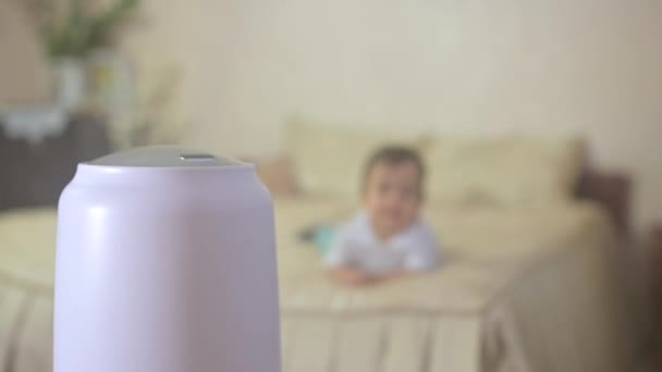 部屋の空気のイオン化と働く加湿器からの蒸気 ぼやけた赤ん坊の上にあり ベッドで遊ぶ 加湿器は作動する 気候装置 — ストック動画