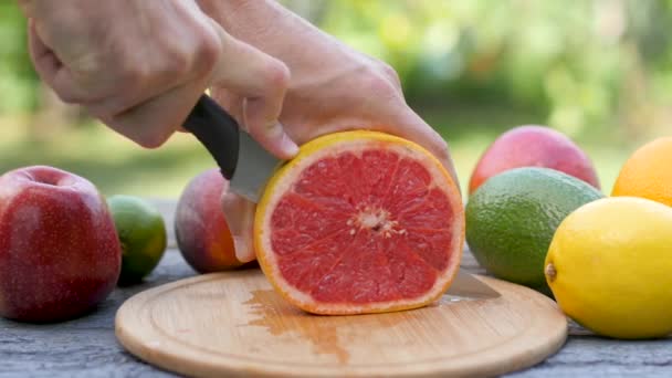 Een Man Snijdt Een Rijpe Grapefruit Plakjes Fruit Een Tafel — Stockvideo