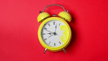 Kırmızı zemin üzerinde beyaz kadranlı sarı alarm saati