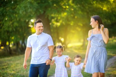 Mutlu bir aile. Aile gün batımında güzel bir parkta yürüyor, aile zamanı..