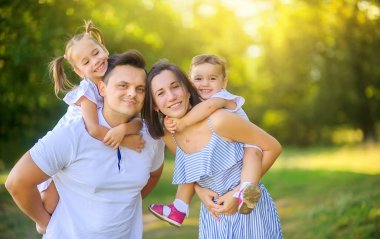 Mutlu bir aile. Aile gün batımında güzel bir parkta yürüyor, aile zamanı..