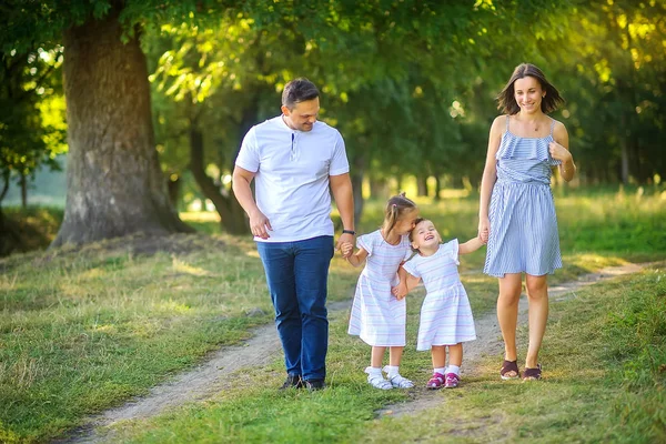Mutlu bir aile. Aile gün batımında güzel bir parkta yürüyor, aile zamanı..