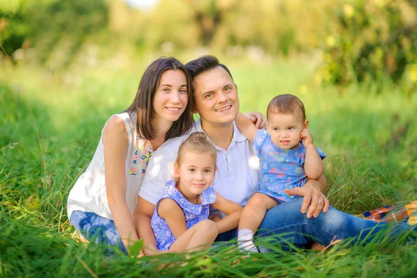 Mutlu bir aile. Aile güzel bir parkta dinleniyor. Çimenlerde oturup, sarılıp gülümsüyor. Aile zamanı..