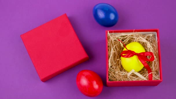 复活节庆祝活动 一只黄色的复活节彩带彩蛋躺在黄色背景的红色礼品盒里 复活节背景 — 图库视频影像