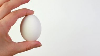 Yakından bir kadın elini tutuyor ve beyaz arka planda bir yumurta gösteriyor. Paskalya süsleri. Paskalya konsepti arka planı.