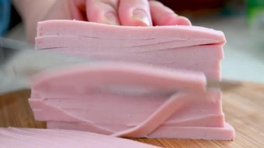 Kadın aşçı, ahşap bir tahtanın üzerinde bir sosisi bıçakla parçalara ayırıyor. Yemek pişirmek..