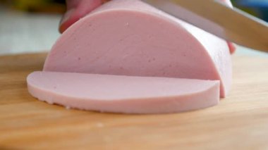 Kadın aşçı, ahşap bir tahtanın üzerinde bir sosisi bıçakla parçalara ayırıyor. Yemek pişirmek..