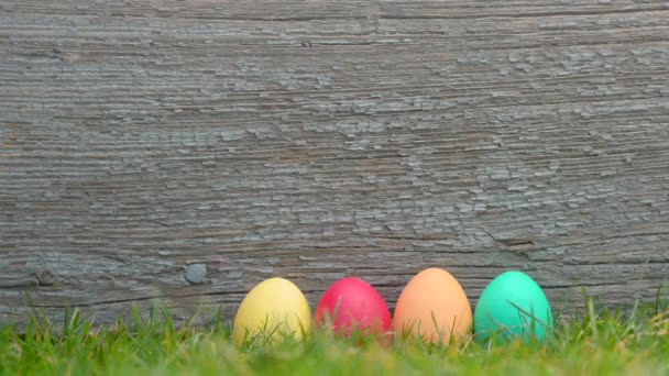Osterfest Bunte Ostereier Auf Dem Rasen Vor Einem Hölzernen Hintergrund — Stockvideo