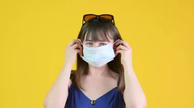 Genç bir kız tıbbi maske takıyor. Sarı arka planda izole edilmiş. sağlık ve tıbbi konsept.