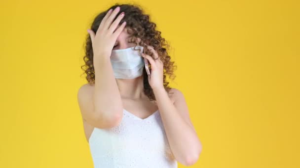 Mladá Dívka Lékařské Masce Mluví Svém Mobilu Izolované Žlutém Pozadí — Stock video