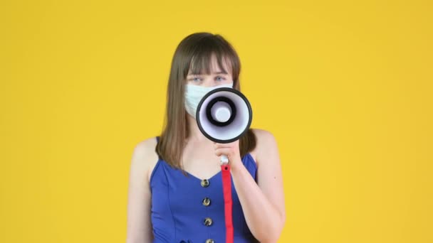 Молода Дівчина Медичній Масці Говорить Через Гучномовця Ізольовані Жовтому Тлі — стокове відео