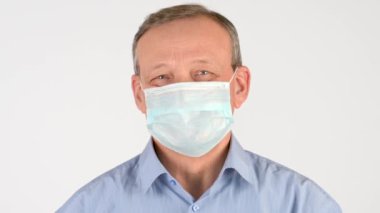 Beyaz arka planda izole edilmiş tıbbi maskeli yaşlı bir adamın yakın plan portresi. Sağlık ve tıbbi konsept. virüs koruması