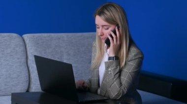 Genç iş kadını telefonda dizüstü bilgisayarla konuşuyor. Ofis masasında oturuyor. Serbest çalışan güzel bir kız..