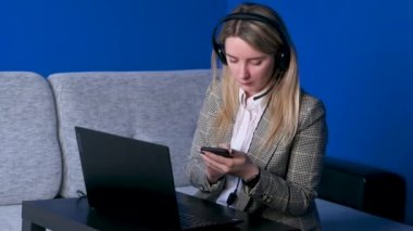Genç serbest çalışan kız konferans görüşmesiyle iletişim kuran kulaklık takıyor ev ofisindeki bilgisayara bakıyor. Bayan öğrenci, internet öğretmenleri konferansı web cam 'den arıyor.