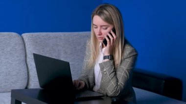 Genç iş kadını telefonda dizüstü bilgisayarla konuşuyor. Ofis masasında oturuyor. Serbest çalışan güzel bir kız..