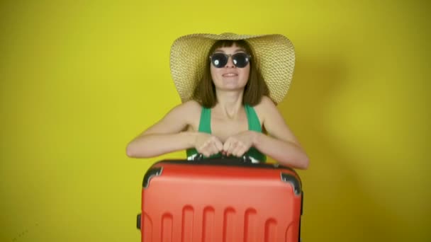 모자와 선글라스를 여행하는 소녀의 가방을 노란색 스튜디오 배경에 미소를 — 비디오