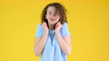 Sarı Stüdyo Arkaplanda Kahverengi Kıvırcık Saçlı, Gülümseyen ve Neşelenen Genç Mutlu Kızın Portresi. İnsanların duyguları..