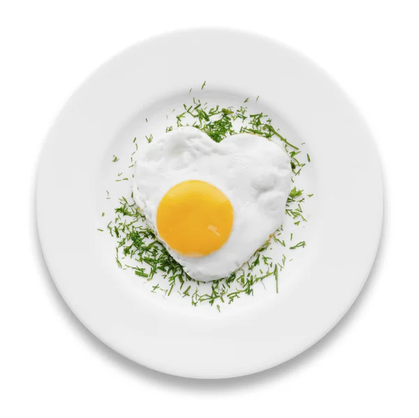 Жареное яйцо в форме сердца с травами на белой тарелке — стоковое фото