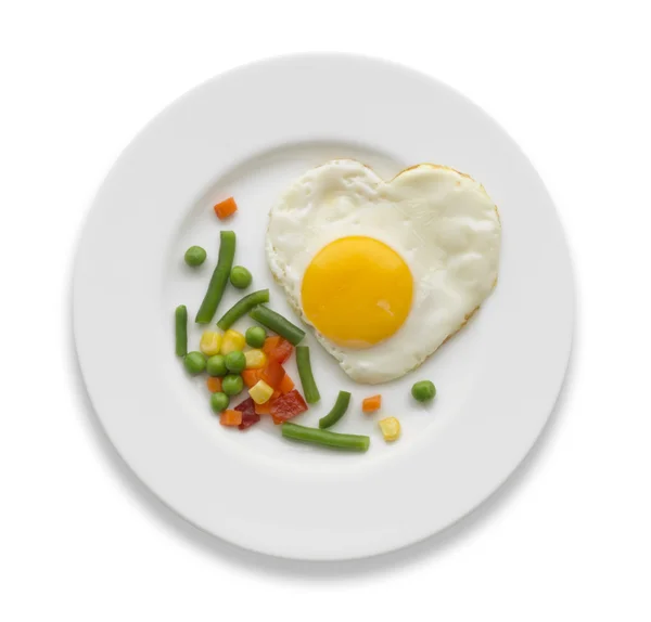 Жареное яйцо в форме сердца и овощи на белом — стоковое фото