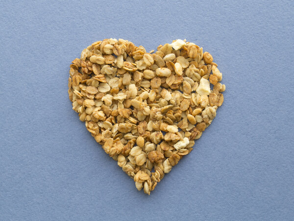 Мюсли в форме сердца на голубом бумажном фоне
