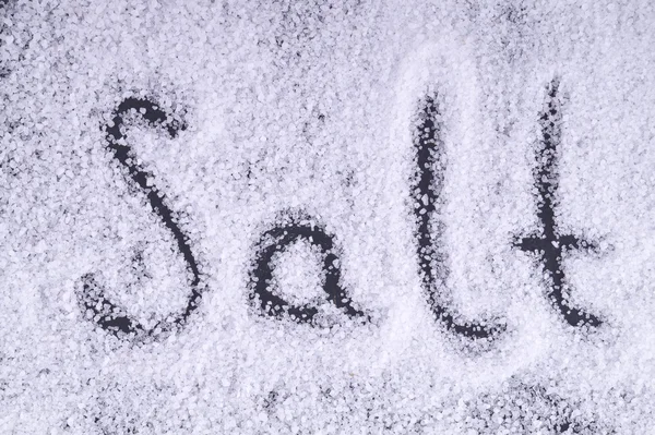 Letras sal sobre os cristais de sal sobre um fundo preto . — Fotografia de Stock