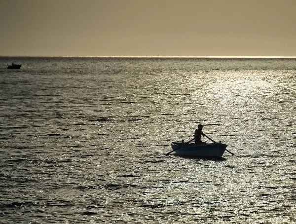 Silhouette of a fisherman in boat — Stock Photo, Image
