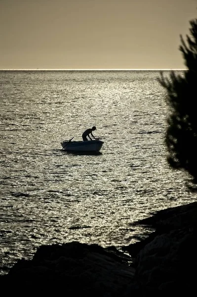 Silhouette of a fisherman in boat — Stock Photo, Image