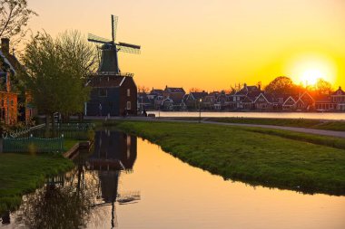 Windmill by a river at suset