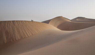 Man in kandura in a desert at sunrise clipart