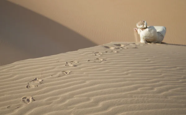 Man in kandura in a desert, playing with sand — Stock Photo, Image