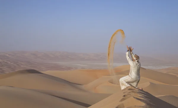 Man in kandura in a desert, throwing sand — Stock Photo, Image