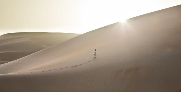Man in kandura in a desert at sunrise — Stock Photo, Image