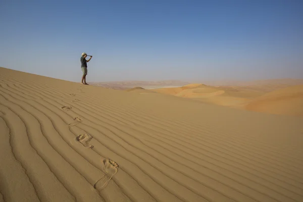 Man looking through spyglass in a desert — Stock Photo, Image
