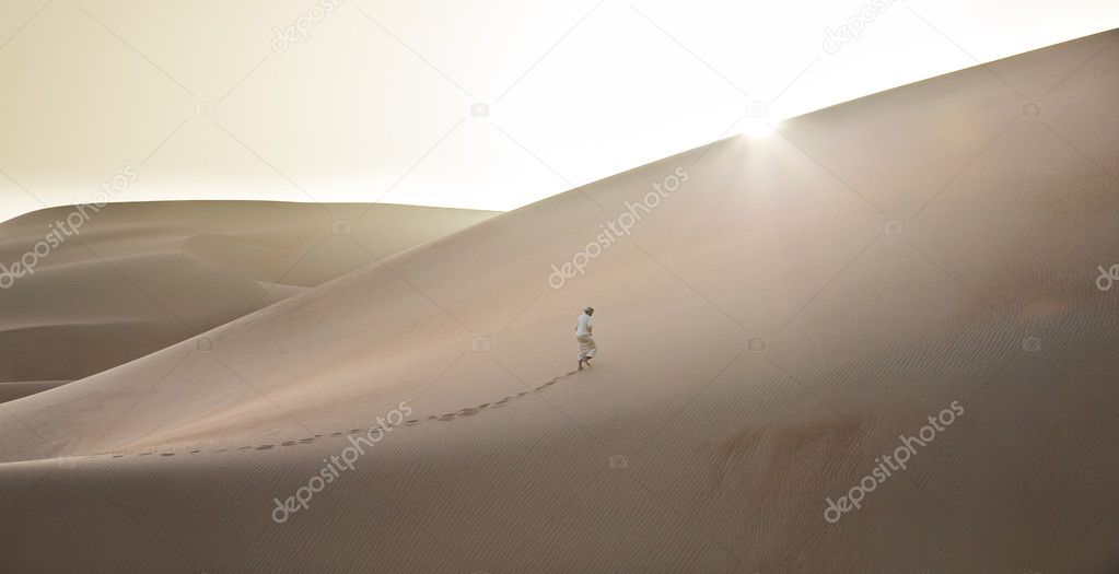 Man in kandura in a desert at sunrise