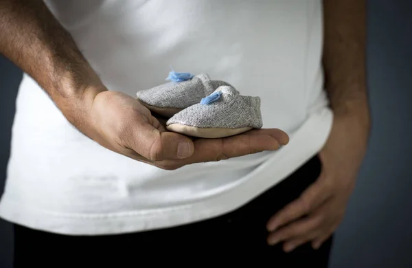 Hombre sosteniendo zapatos de bebé — Foto de Stock