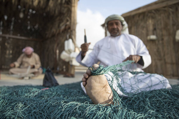 omani man reparing fish net