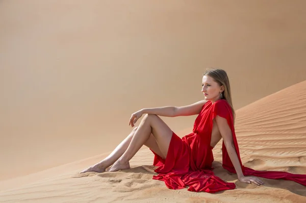 Žena v červených šatech v poušti — Stock fotografie